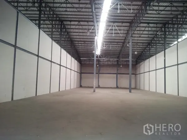 货栈 出租在Mueang Samut Sakhon, Samut Sakhon - 仓库内部空间开阔，钢梁高棚顶与混凝土地面。