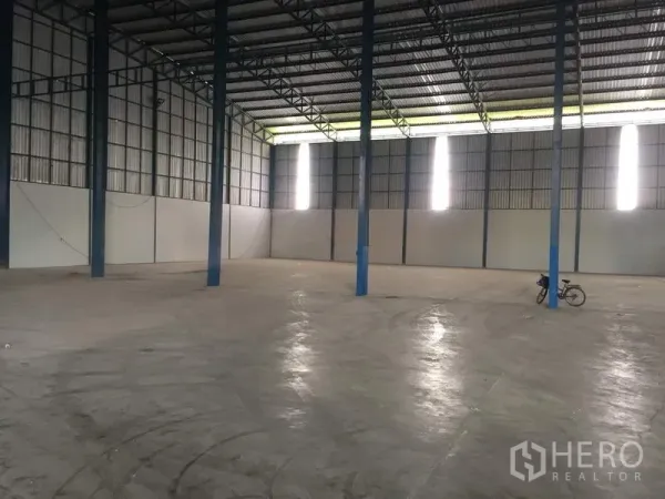 Warehouse for rent in Pathum Thani - Spacious warehouse interior featuring high steel trusses and a polished concrete floor.