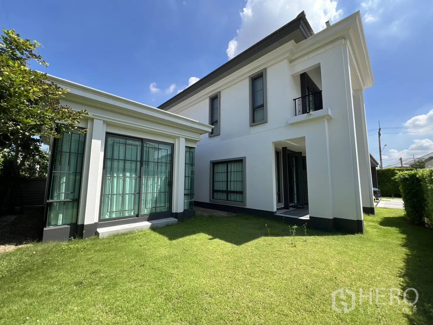 Detached House for rent or sale in Mueang Pathum Thani, Pathum Thani - Side garden with lush lawn and glass-walled pavilion connected to the main house.