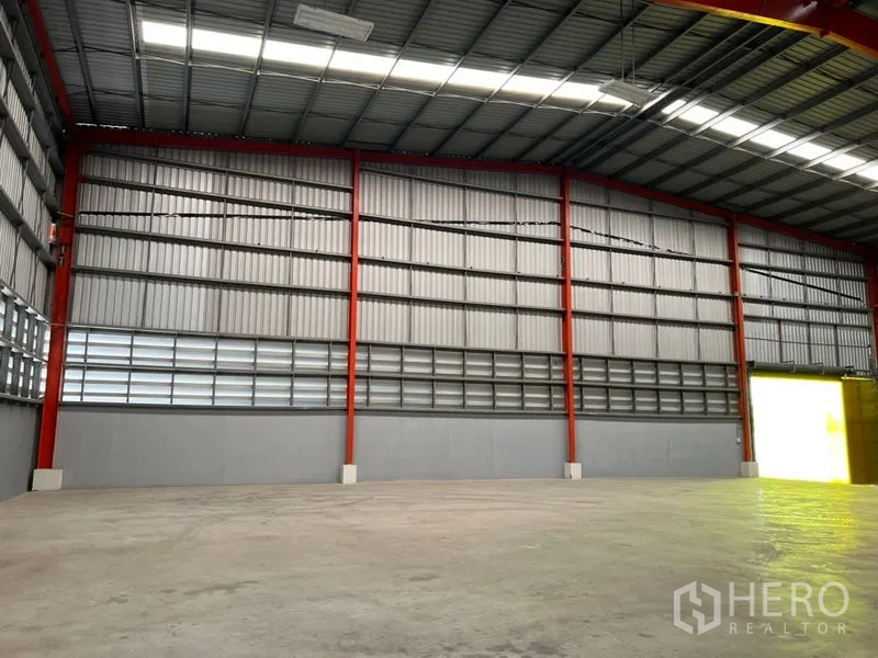 Warehouse for rent in Pathum Thani - Warehouse interior showing high ceiling, red steel columns, and smooth concrete floor.