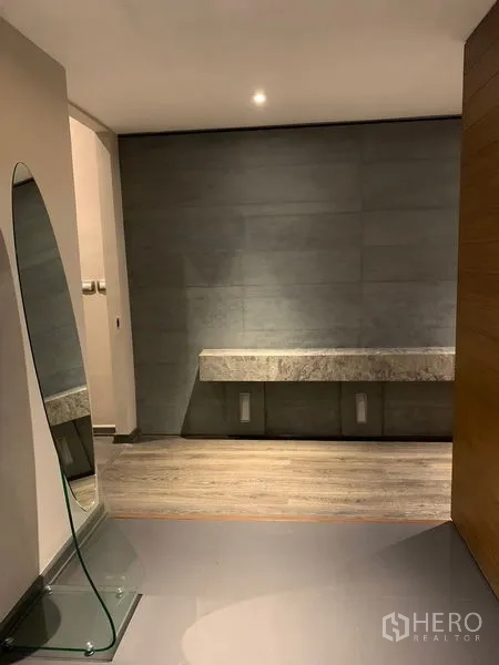 Condominium for rent - Minimalist hallway with leaning mirror and stone console with accent lighting.
