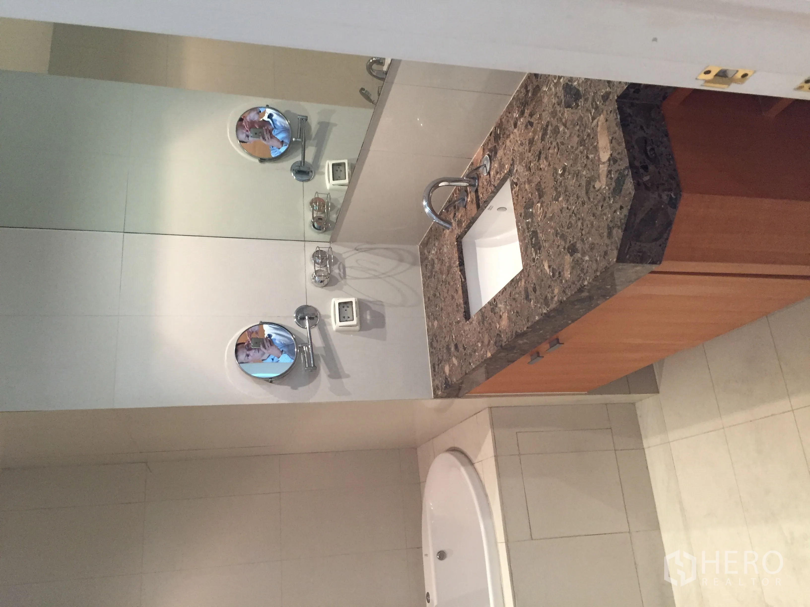 Condominium for rent or sale in Pathum Wan, Bangkok - Bathroom featuring a stone countertop vanity, circular mirrors and a bathtub.