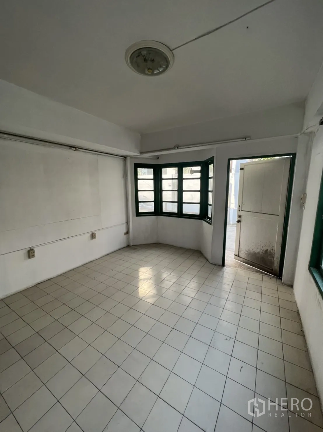 Townhouse for sale in Watthana, Bangkok - Ground-floor living area with bay windows and a door opening to the front patio.