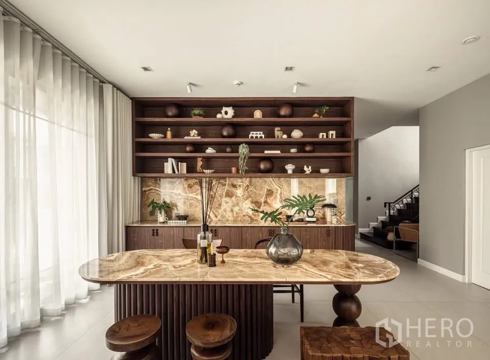 Detached House for rent or sale in Lat Krabang, Bangkok - Dining area with marble-top table, display shelves, and a stone backsplash near the stairs.