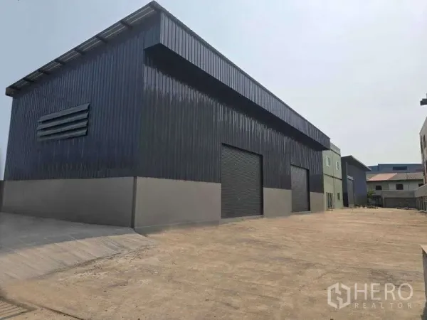 คลังสินค้า ให้เช่าในMueang Samut Sakhon, Samut Sakhon - ด้านนอกโกดังสีดำยาว มีประตูม้วนหลายบานและทางเข้าออกกว้าง