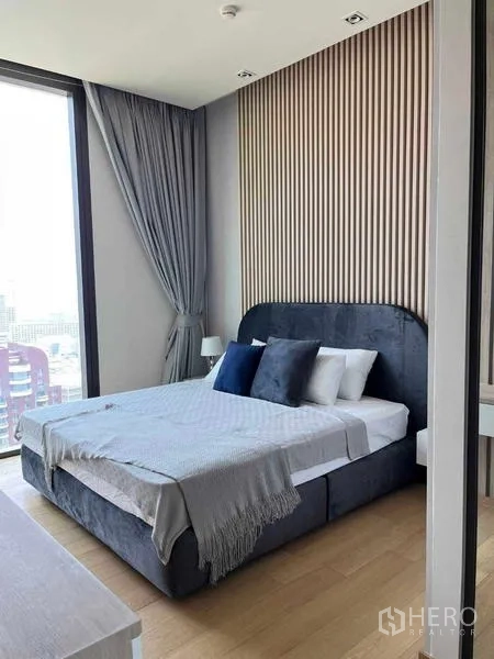 Condominium for rent - Master bedroom with upholstered bed, slatted accent wall, large window with city view, and grey drapes.