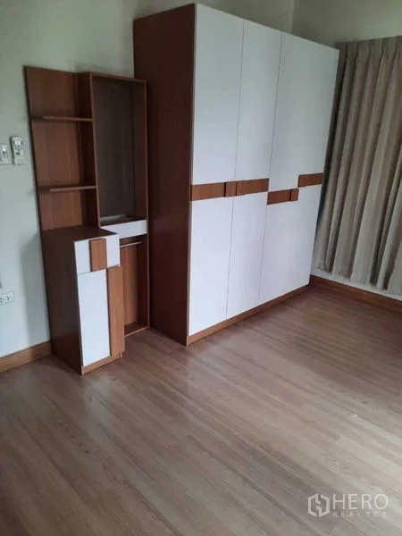 Home Office for rent in Watthana, Bangkok - Built-in wardrobe and shelving in a bright room with wood flooring.