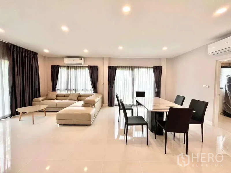 Detached House for rent in Don Mueang, Bangkok - Open-plan living and dining area with L-shaped sofa and six-seat dining table.