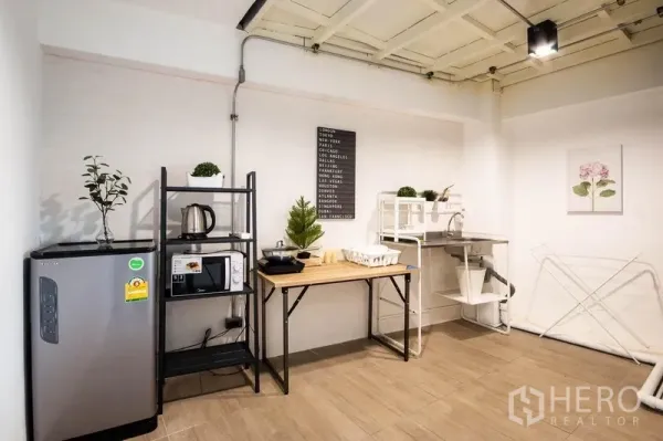 带办公室的家 出租在Phaya Thai, Bangkok - 茶水间一角，含冰箱、操作台与收纳架，木纹地砖。