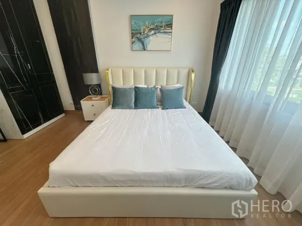 Detached House for rent or sale in Bang Phli, Samut Prakan - Bright bedroom with white upholstered bed, teal cushions, large window and wood floor.