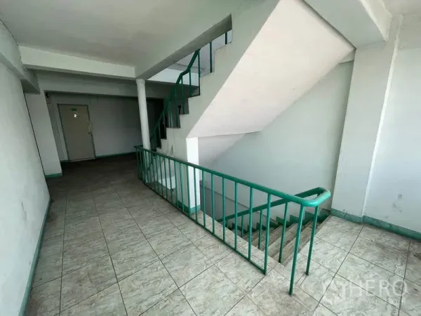 Apartment for sale in Mueang Samut Prakan, Samut Prakan - Stairwell landing with green metal railings and tiled flooring.
