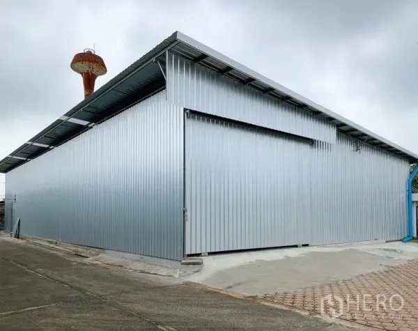 货栈 出租在Mueang Pathum Thani, Pathum Thani - 邦蓬区金属板仓库外观，滑动大门与铺装车道，巴吞他尼。
