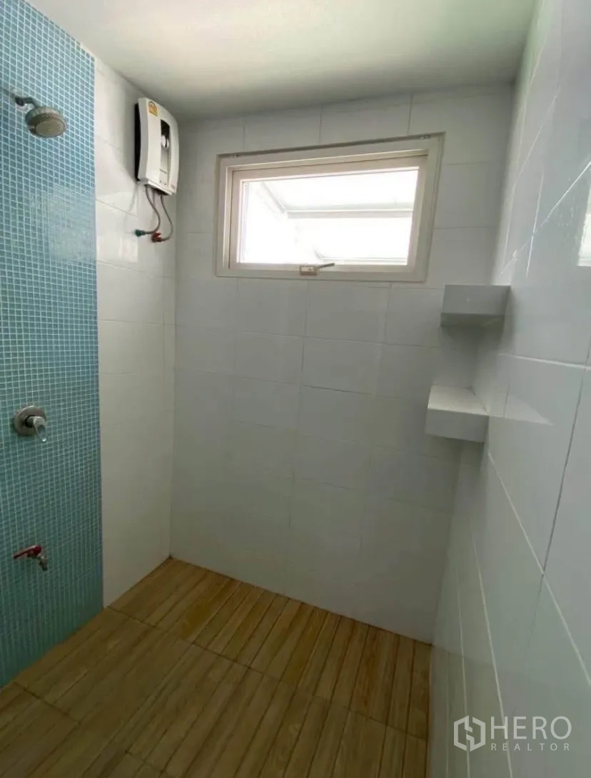 联排别墅 for rent in Phra Khanong, Bangkok - 淋浴房带蓝色马赛克装饰墙、电热水器与木纹地面。