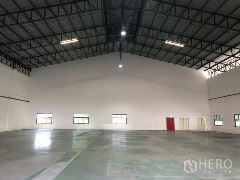 货栈 出租 - 仓库端墙视图，高棚照明与服务门。