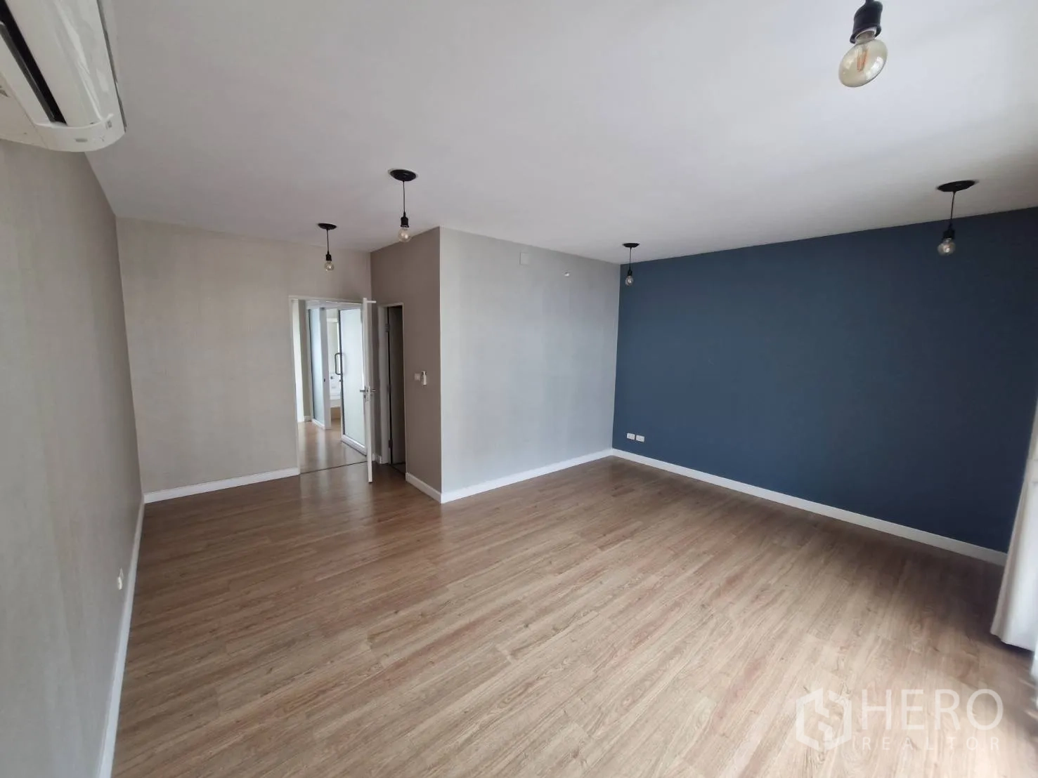 Townhouse for sale in Rat Burana, Bangkok - Large multipurpose room with blue feature wall and wood floors.