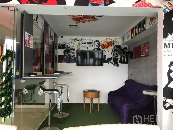 零售空间 出租在Watthana, Bangkok - 紧凑的室内区，设壁挂电视、吧椅、小圆桌与沙发，配有流行艺术风格墙面。