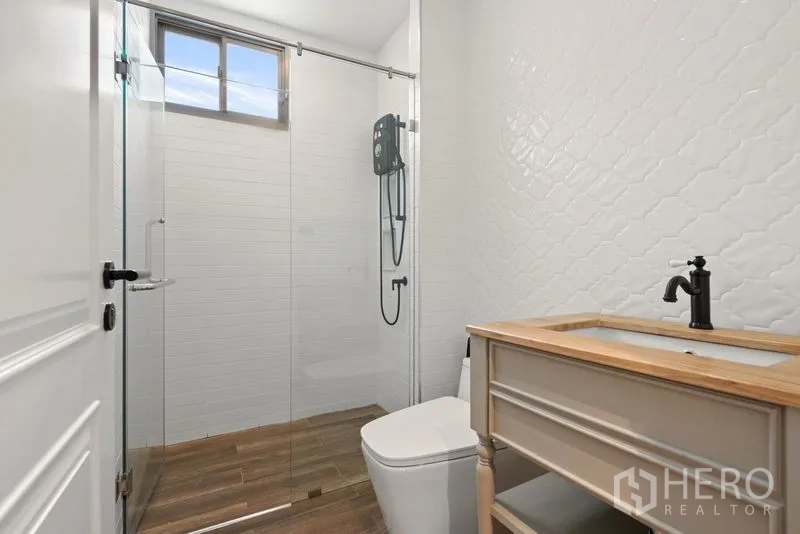 บ้าน ขาย - ห้องน้ำแขกพร้อมตู้กระจกอาบน้ำ กระเบื้องสีขาว และเคาน์เตอร์ไม้