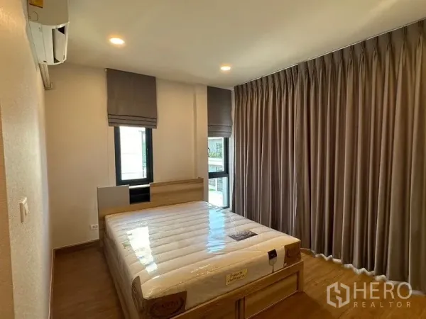 Detached House for rent in Bang Phli, Samut Prakan - Bright bedroom with queen bed, wood flooring, full-length curtains and wall-mounted air conditioner.