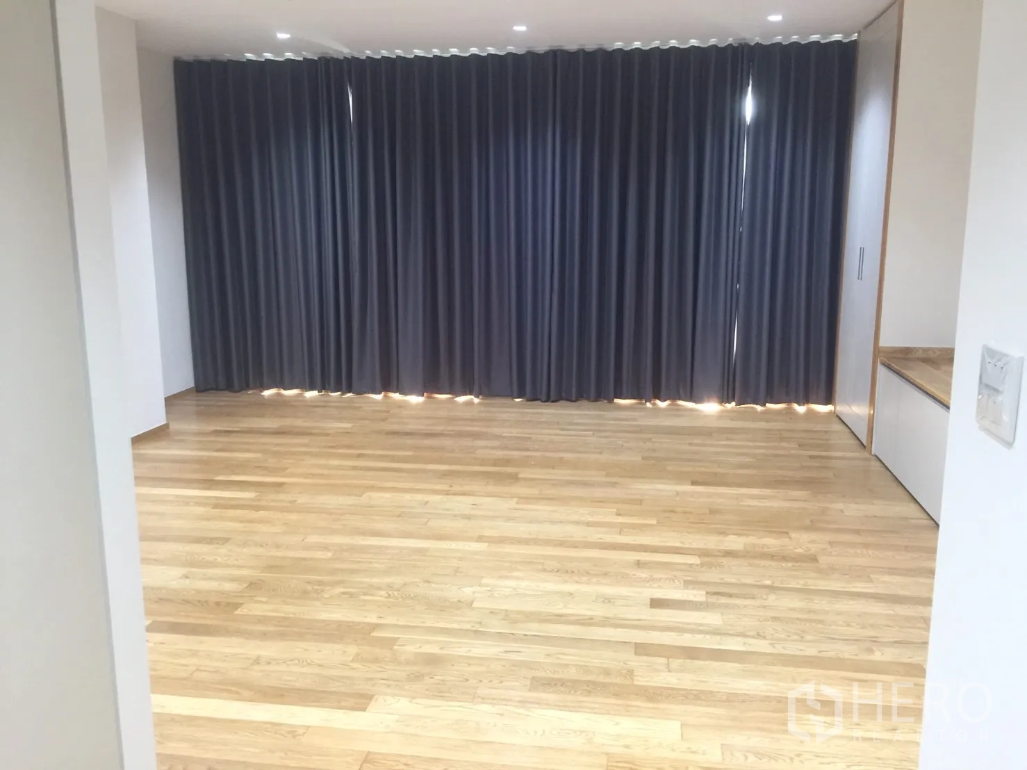 คอนโด for ในWatthana, Bangkok - ห้องนั่งเล่นขนาดใหญ่ ผ้าม่านเต็มผนังสีเข้ม ไฟฝังเพดาน และพื้นไม้จริง