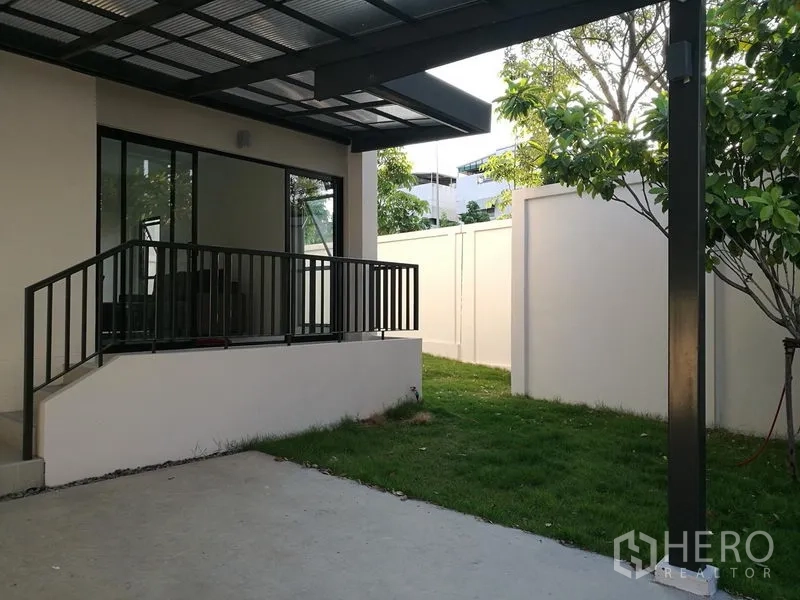 Townhouse for rent in Saphan Sung, Bangkok - Covered terrace opening to a small private lawn with a white boundary wall.