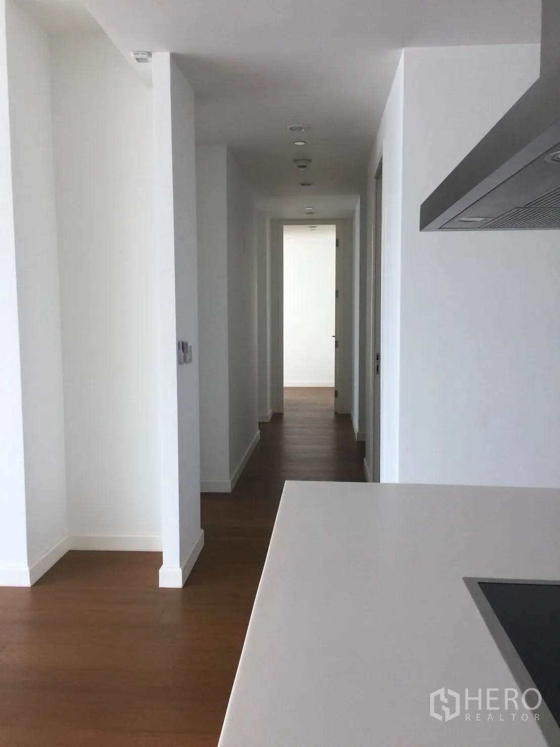 Condominium for rent in Pathum Wan, Bangkok - Bright hallway with white walls and wooden floors leading to bedrooms.