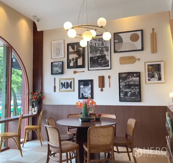 零售空间 出租在Watthana, Bangkok - 靠窗圆桌区，吊灯与藤椅、装饰画点缀。