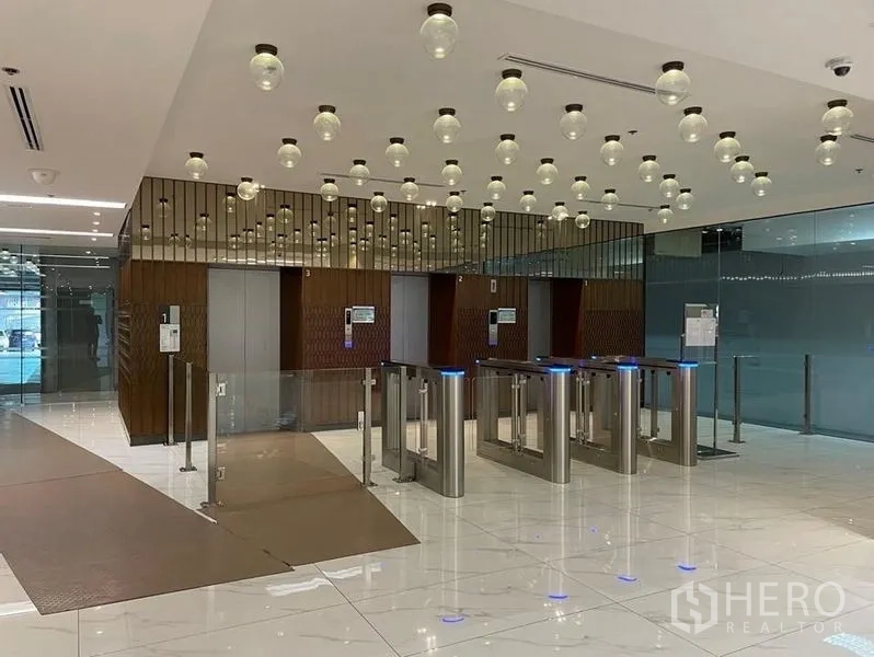 办公空间 出租在Bang Rak, Bangkok - 现代化大堂，设安保闸机、电梯与装饰吊灯，地面光洁明亮。