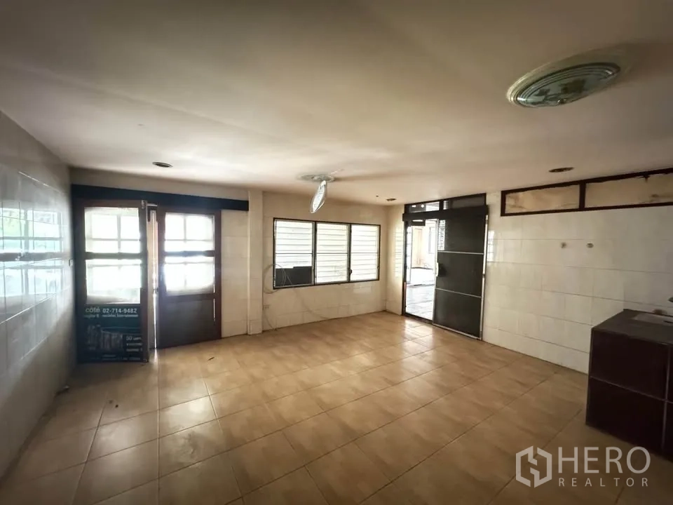 Detached House for rent or sale in Watthana, Bangkok - Large tiled kitchen or workspace with exterior doors and louvered windows.