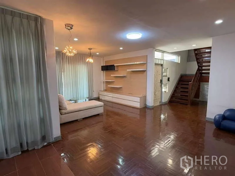 Detached House for rent in Bang Kapi, Bangkok - Open‑plan living area showing media wall, sofa space and stairs.
