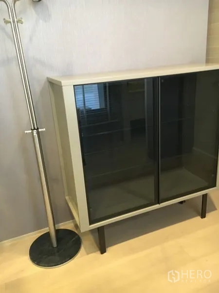 独立式住宅 出租在Wang Thonglang, Bangkok - 浅木地板上的玻璃双门矮柜，旁有金属衣帽架。