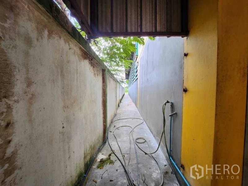 货栈 出租在Lat Krabang, Bangkok - 建筑侧面狭长通道，墙间放置水管