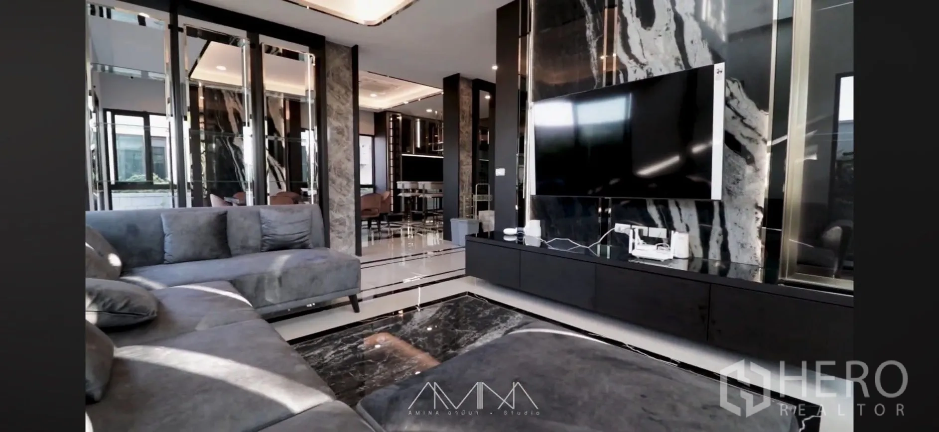 Detached House for rent in Saphan Sung, Bangkok - Open-plan living room with large TV on a marble accent wall and gray sectional sofa.