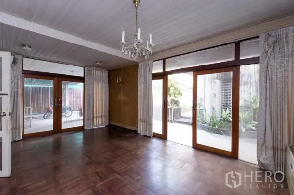 บ้าน ให้เช่าในKhlong Toei, Bangkok - ห้องกว้างพื้นปาร์เกต์ โคมระย้า และประตูกระจกเต็มบานเปิดสู่ลานพักผ่อนและสวน