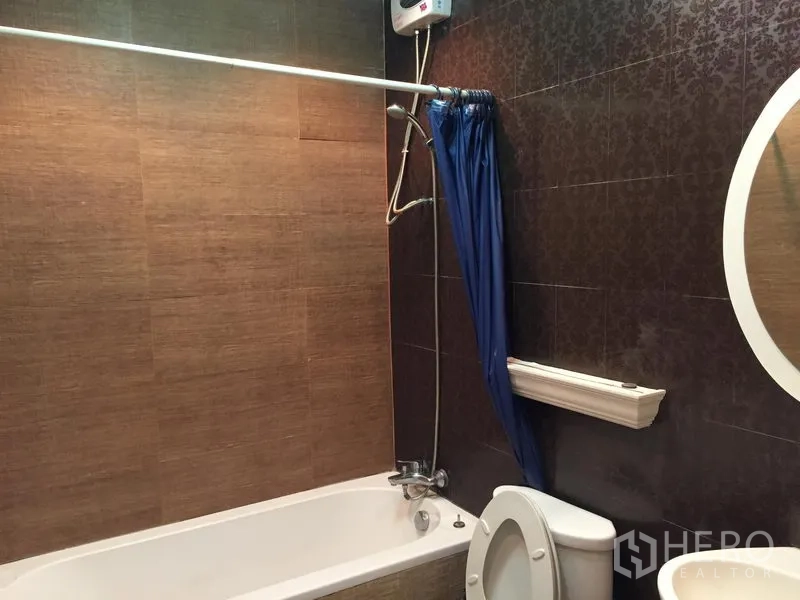 ทาวน์เฮาส์ ให้เช่าในChatuchak, Bangkok - ห้องน้ำพร้อมอ่างอาบน้ำ ฝักบัวเหนืออ่าง ผ้าม่านกันน้ำ และผนังลายสีน้ำตาล