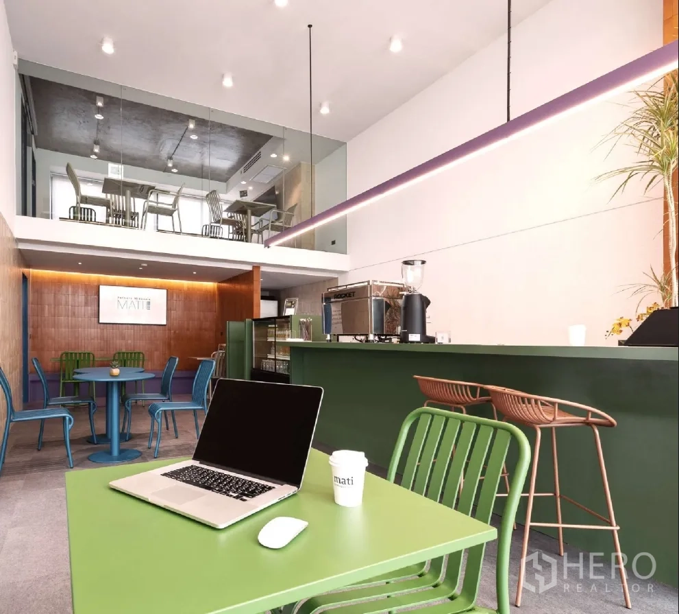 家庭办公室 for rent or sale in Bang Khen, Bangkok - 开放式工作区，设咖啡吧台、彩色桌椅与夹层座位，顶置轨道灯。