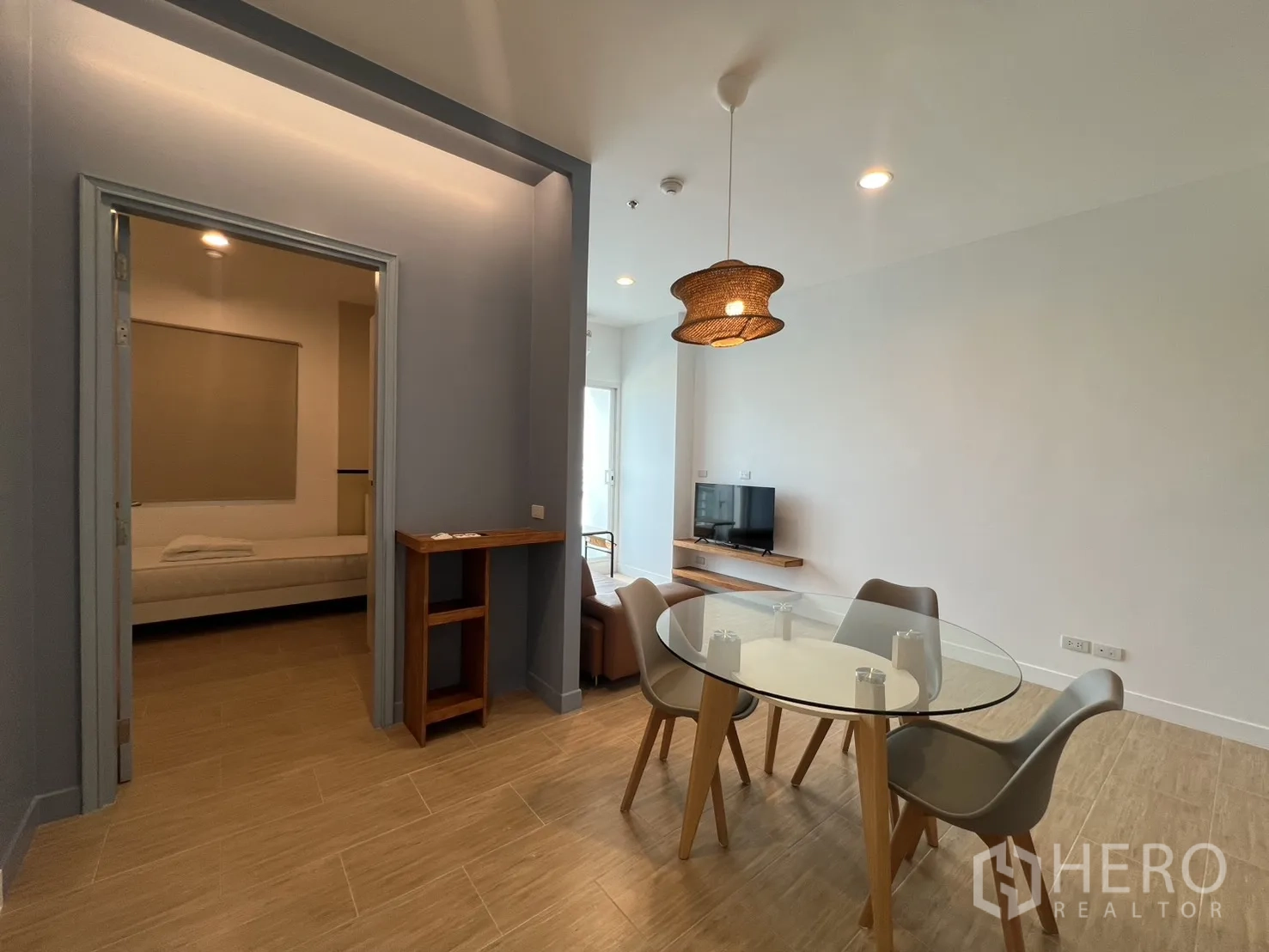 Condominium for rent in Bang Kapi, Bangkok - View toward the dining table with a woven pendant light and bedroom doorway.