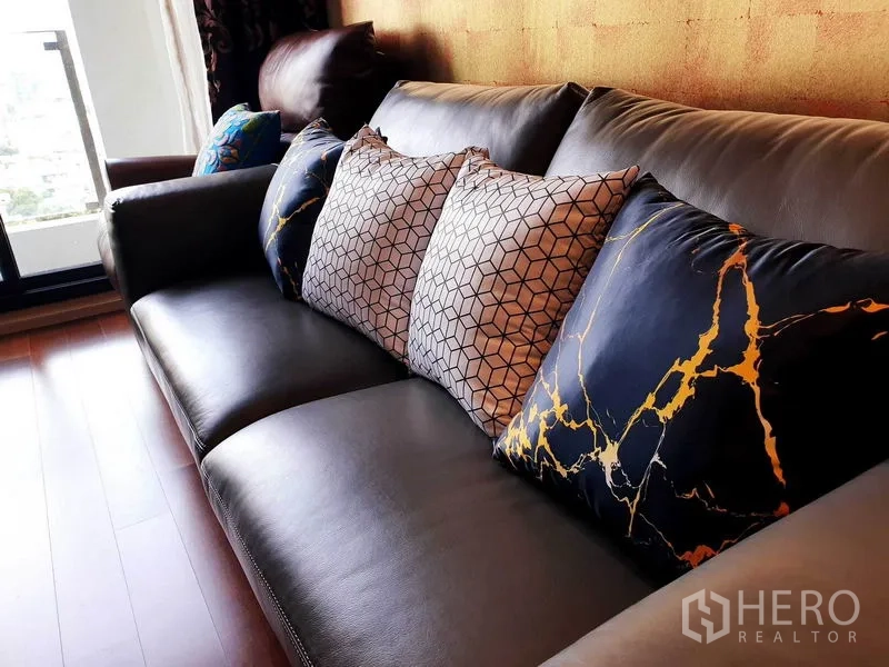คอนโด ให้เช่าหรือขายในWatthana, Bangkok - โซฟาหนังพร้อมหมอนลายกราฟิก ใกล้ประตูกระจกระเบียง