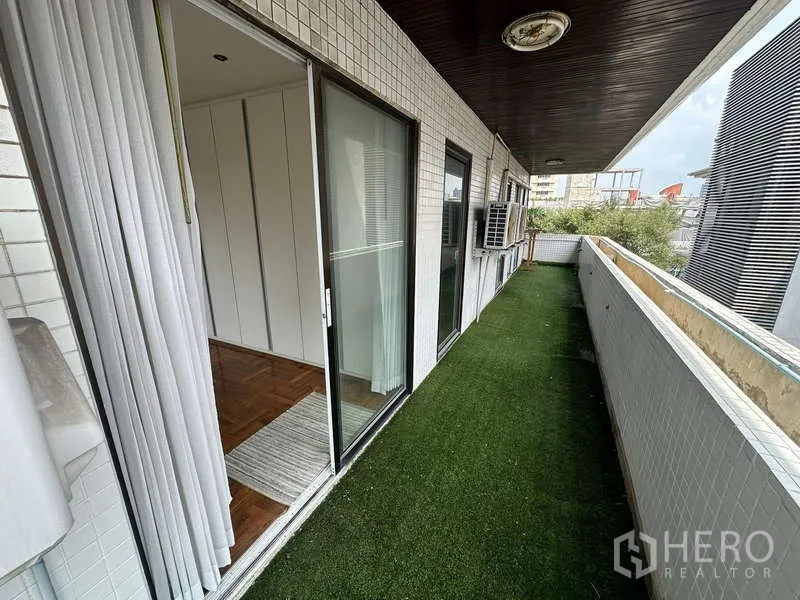 คอนโด ให้เช่าในWatthana, Bangkok - ระเบียงยาวมีหญ้าเทียม ประตูบานเลื่อนกระจก และคอมเพรสเซอร์แอร์ภายนอก
