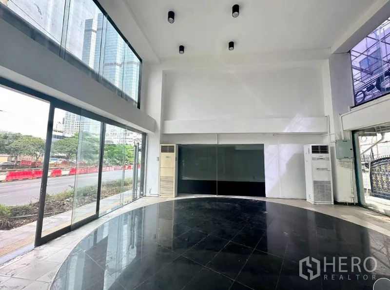 Retail Space for rent in Sathon, Bangkok - Open retail space with full-height windows, city view, and two standing air conditioners.