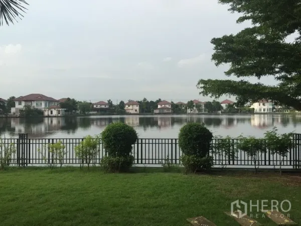 บ้าน ให้เช่าหรือขายในLat Krabang, Bangkok - สนามหญ้าส่วนตัว รั้วเหล็ก มองออกไปเห็นทะเลสาบและบ้านรอบๆ.