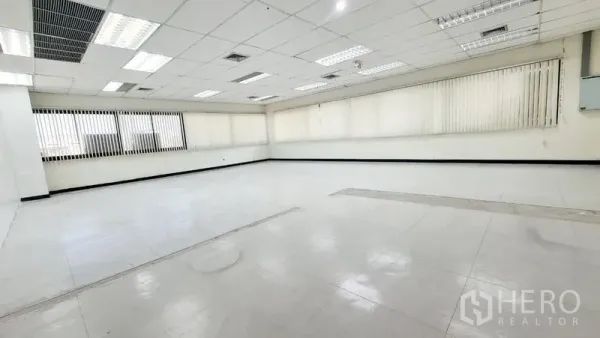 Office Space for rent in Watthana, Bangkok - Corner view of a bright workspace with long windows and vertical blinds.