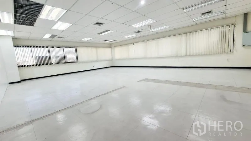 Office Space for rent in Watthana, Bangkok - Corner view of a bright workspace with long windows and vertical blinds.