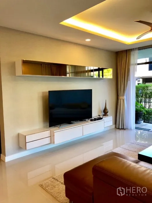 Detached House for rent in Bang Kapi, Bangkok - Media wall with large flat-screen TV, floating cabinets and sliding doors to the patio.