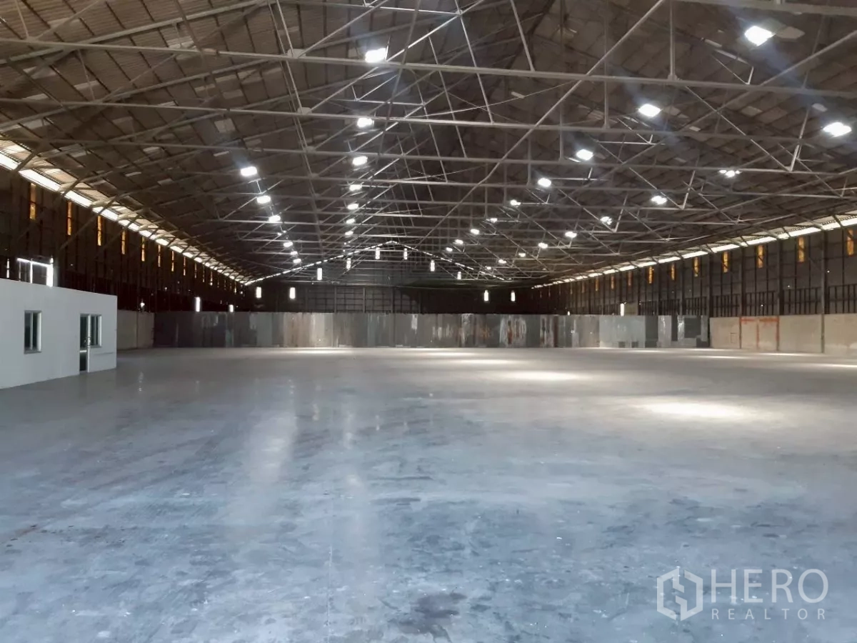 Warehouse for rent in Pak Kret, Nonthaburi - Wide warehouse overview with built-in office rooms, tall roof structure and unobstructed open space.