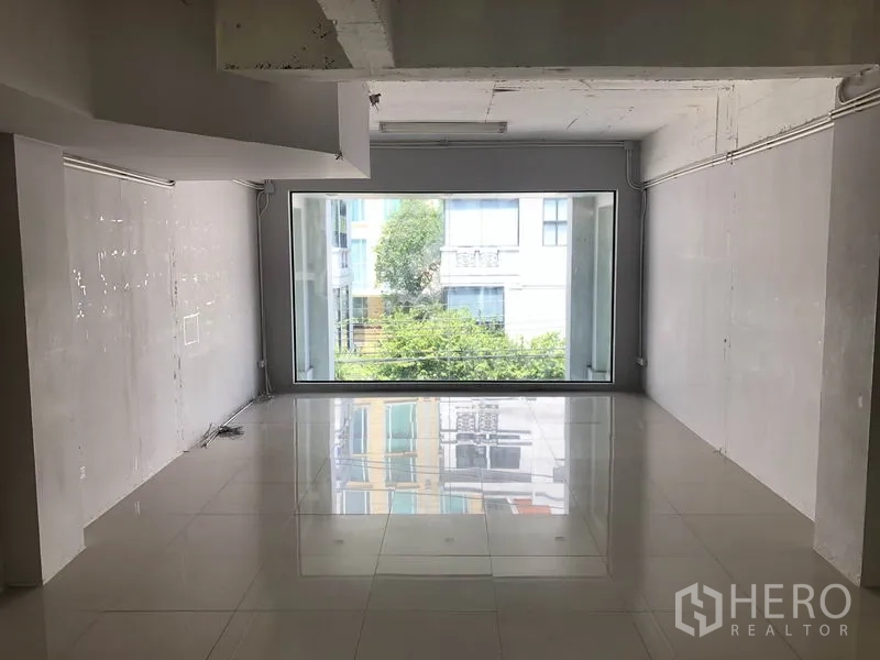 Office Space for rent in Khlong Toei, Bangkok - Bright empty office with glossy tile floors and a full-width window overlooking greenery.