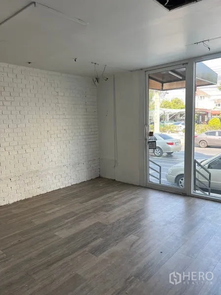 店屋 出租在Wang Thonglang, Bangkok - 临街玻璃入口，采光充足，白砖墙与木地面，适合陈列展示。