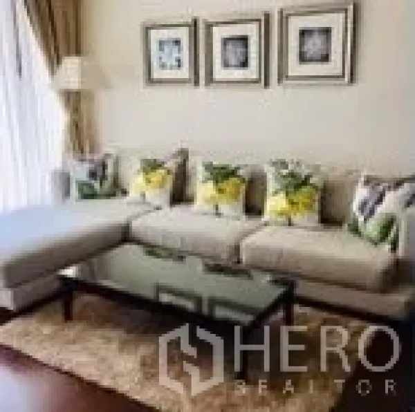 公寓 出租在Watthana, Bangkok - 客厅一角，L型沙发、玻璃茶几、地毯与墙面装饰画