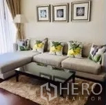 公寓 出租在Watthana, Bangkok - 客厅一角，L型沙发、玻璃茶几、地毯与墙面装饰画