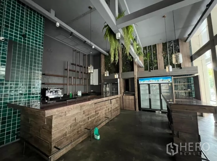 零售空间 出租 - 吧台区配玻璃门冰柜、吊灯与外露梁。