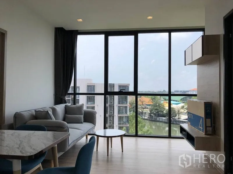 คอนโด ให้เช่าในWatthana, Bangkok - ห้องนั่งเล่นสว่างโปร่ง ผนังกระจกเต็มบาน โซฟาและพื้นที่ทานอาหาร มองเห็นวิวคลองและเมือง